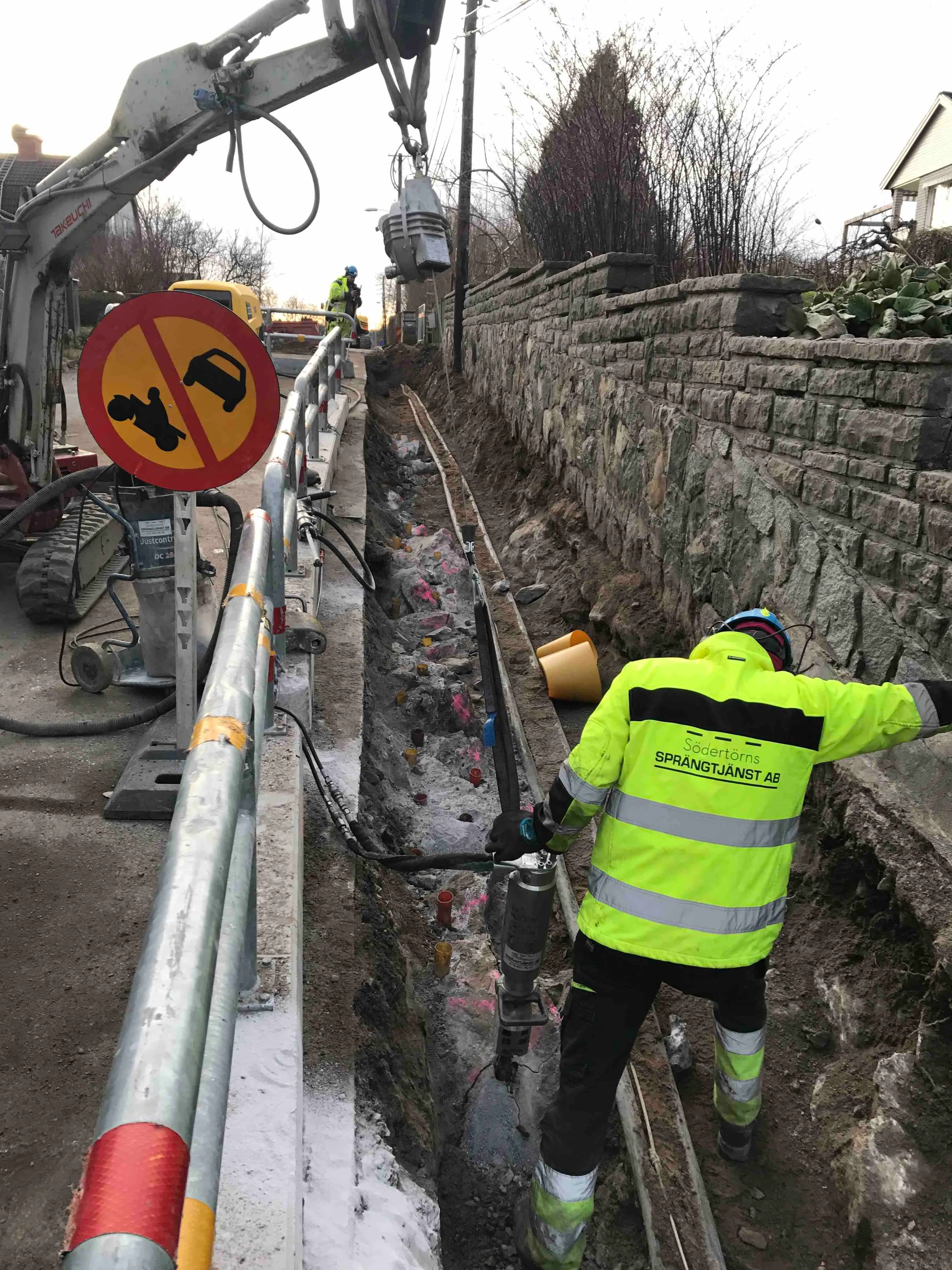 Bergspräckning intill väg och stödmur i tätort