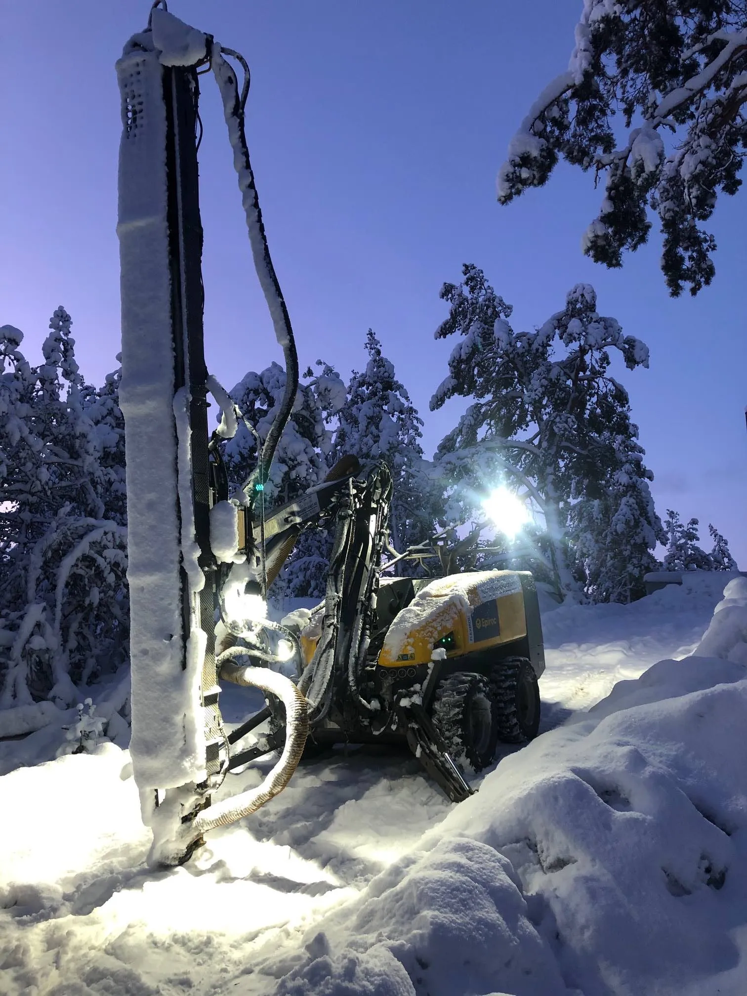 Borrigg med tänd arbetsbelysning vid skymning i vinterlandskap